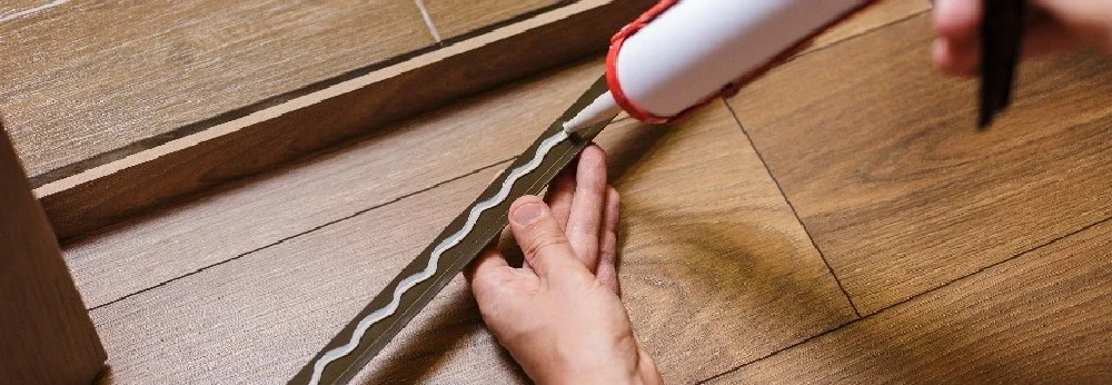 Person trägt Klebstoff auf Metallleiste auf